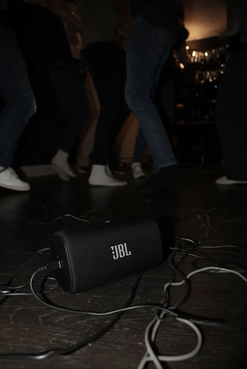 A speaker on the floor and the feet of the people dancing around it.