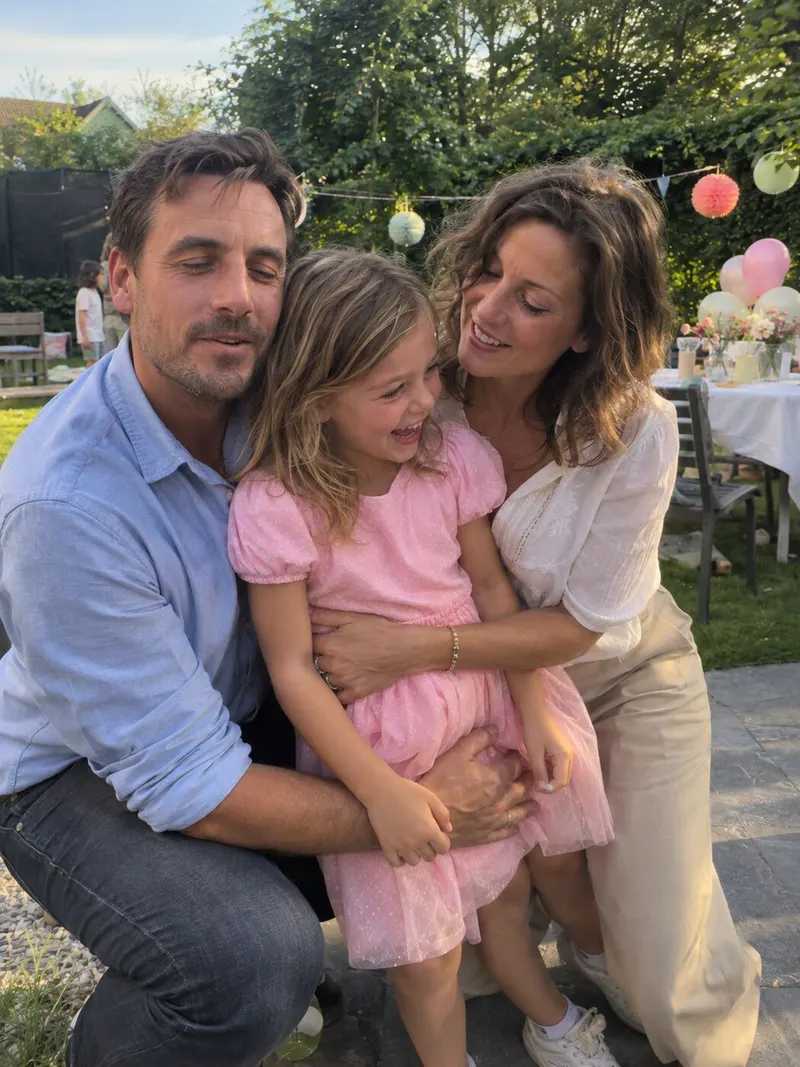 Parents hug their daughter in the garden.