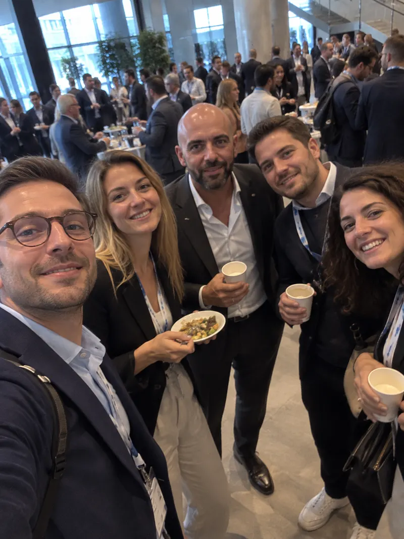 A group of colleagues smile for a selfie during a conference break.
