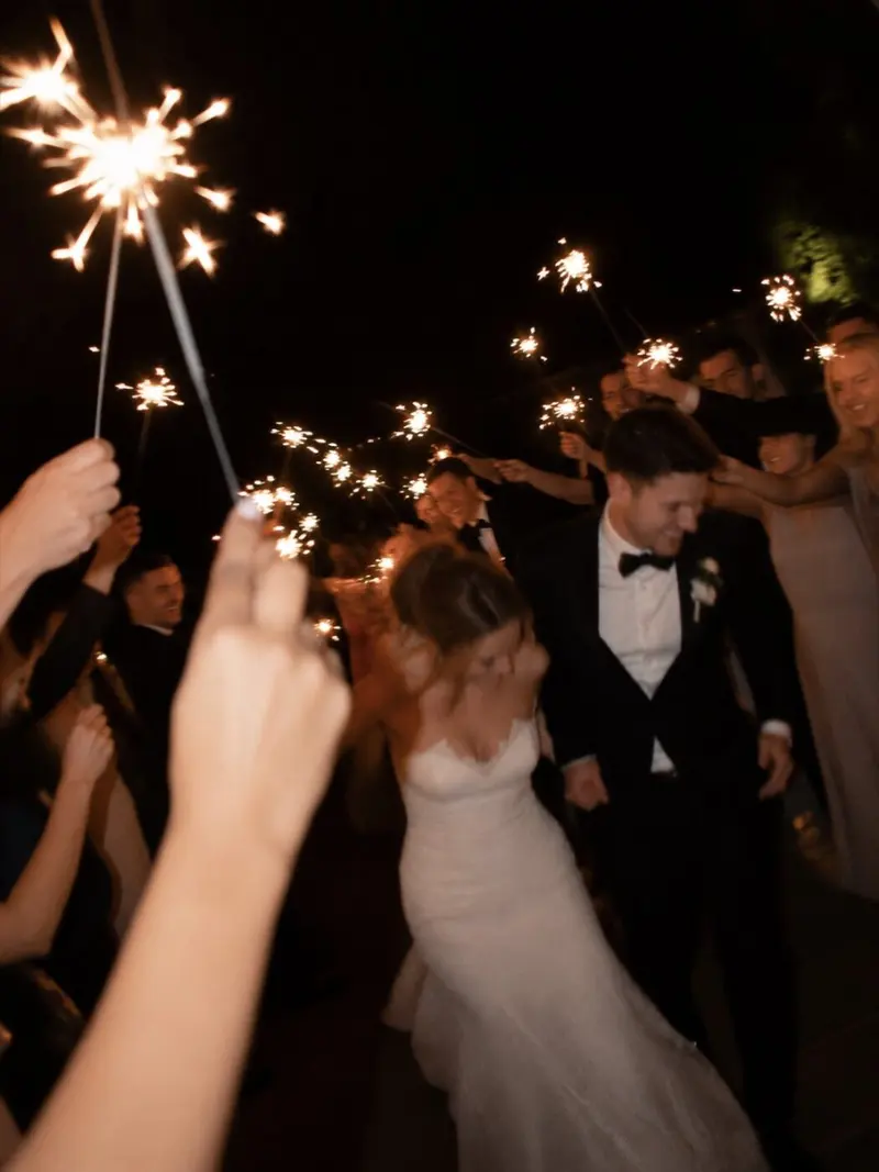 The newlyweds walk through a tunnel of sparklers held by their guests.