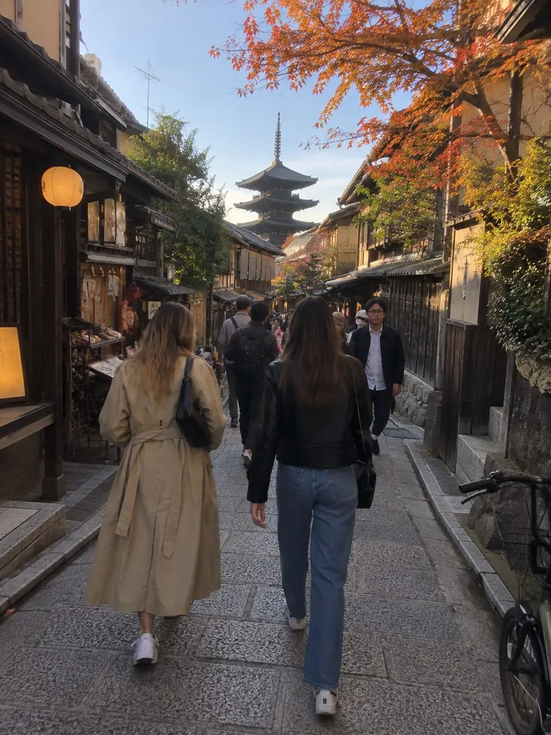 Two friends walk down a Kyoto lane toward a pagoda.